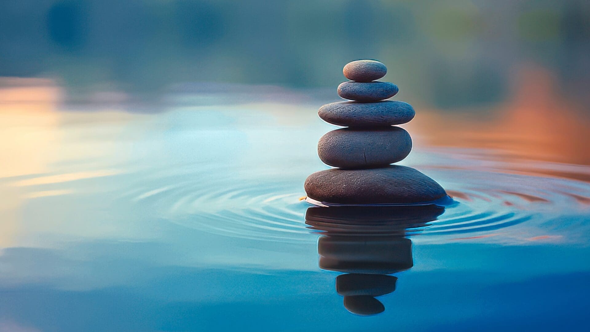 Stacked stones balanced on water, symbolizing peace and harmony.