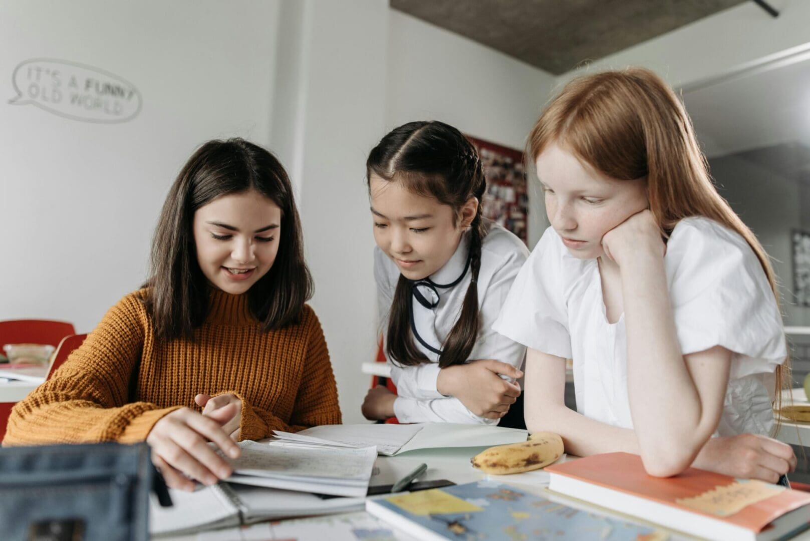 Three young women studying together at a table with books and notes.