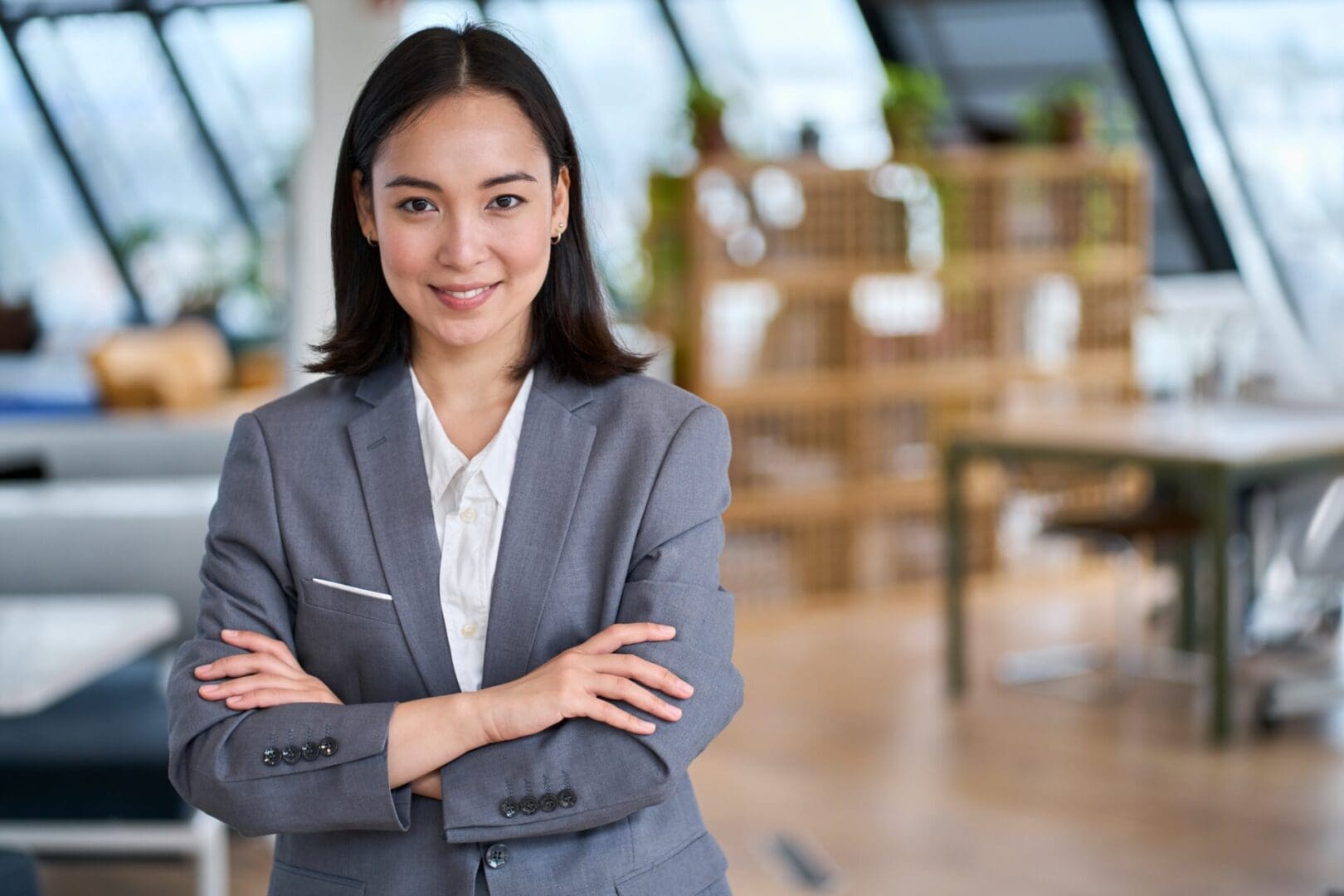 Confident businesswoman standing with arms crossed in an office.