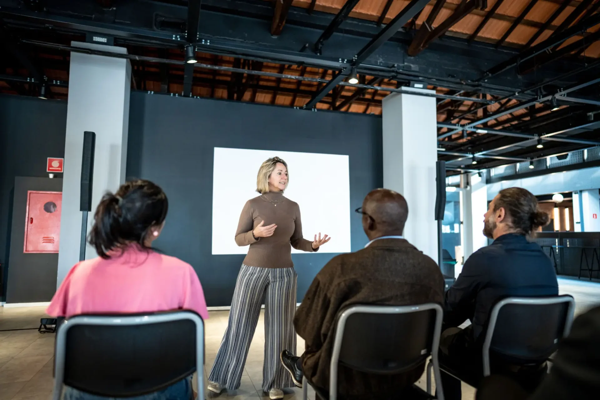 A speaker addressing an audience in a modern indoor setting.