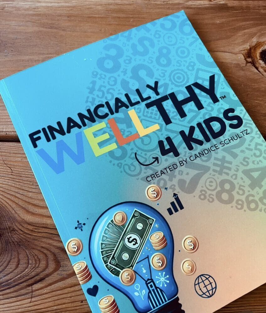 A book titled 'Financially Wellthy 4 Kids' with coins and a calculator on a wooden surface.