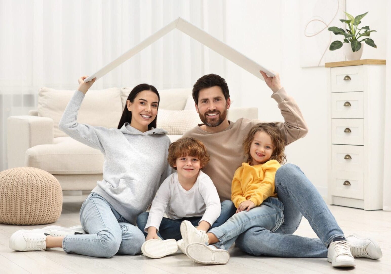 Happy family sitting together making a roof shape with their hands.